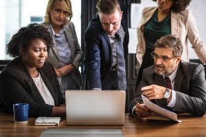 Business employees surrounding laptop discussing