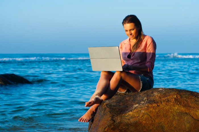 Woman working remotely on a beach