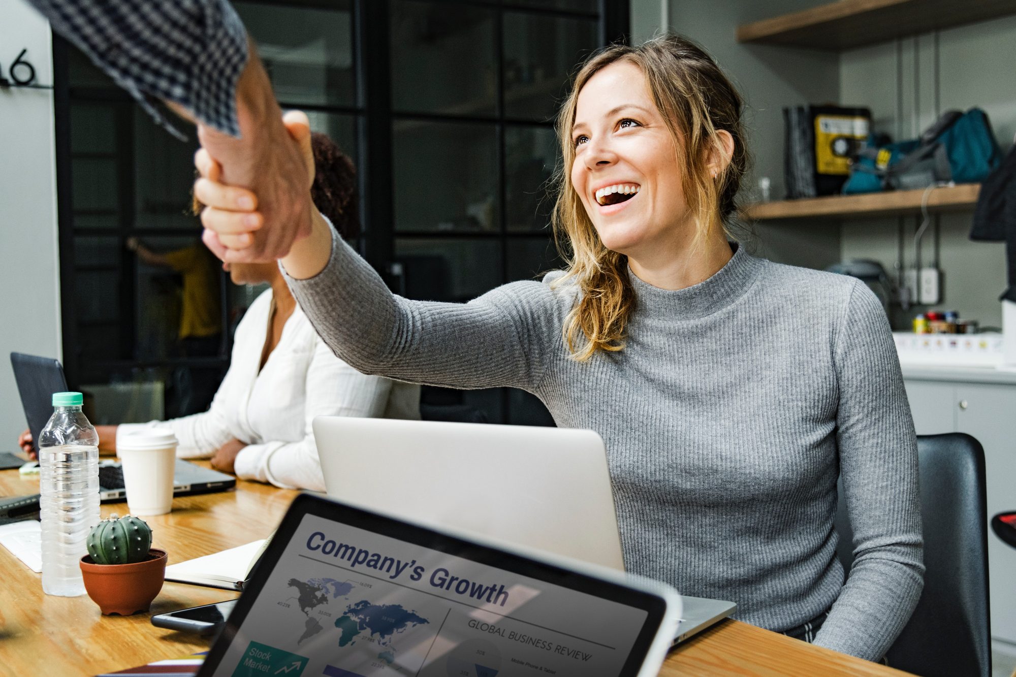 Business Interactions around laptop- shaking hands