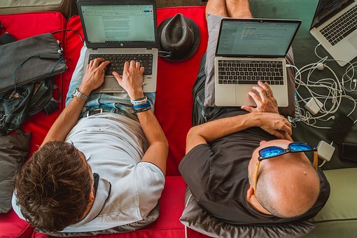 Two guys working on laptops together