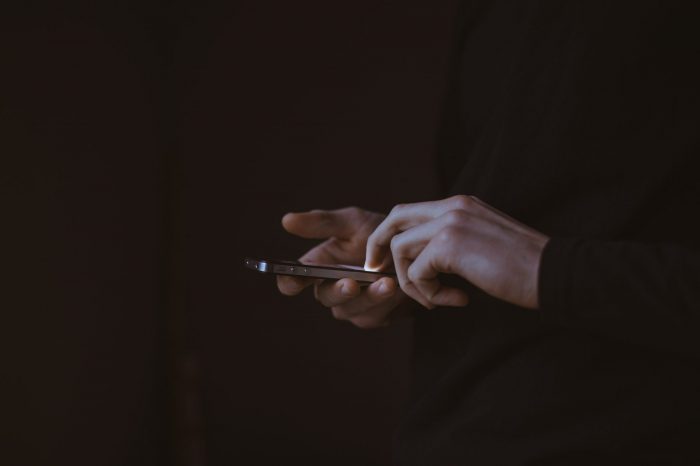 Hands holding a smart phone in the dark