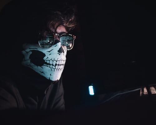 A computer hacker wearing a skull-mask