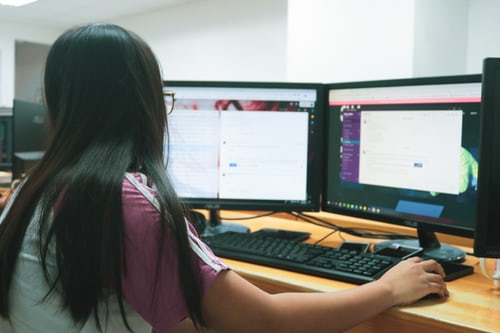 Woman working on dual monitors