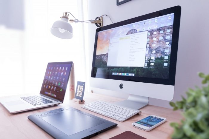 A computer, iPad, and iPhone on a desk 