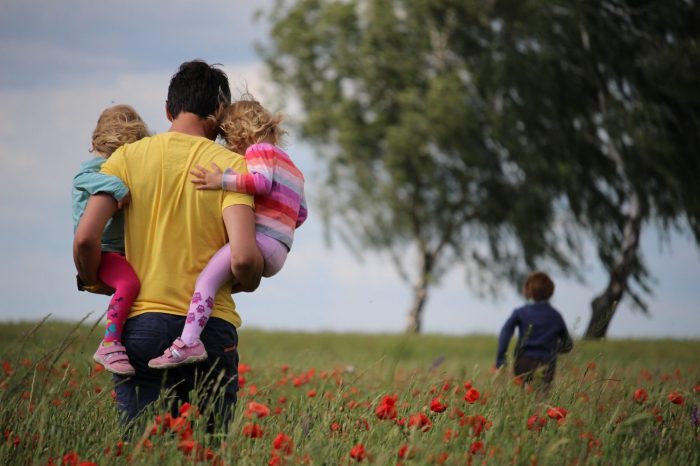 A father holding his two daughters