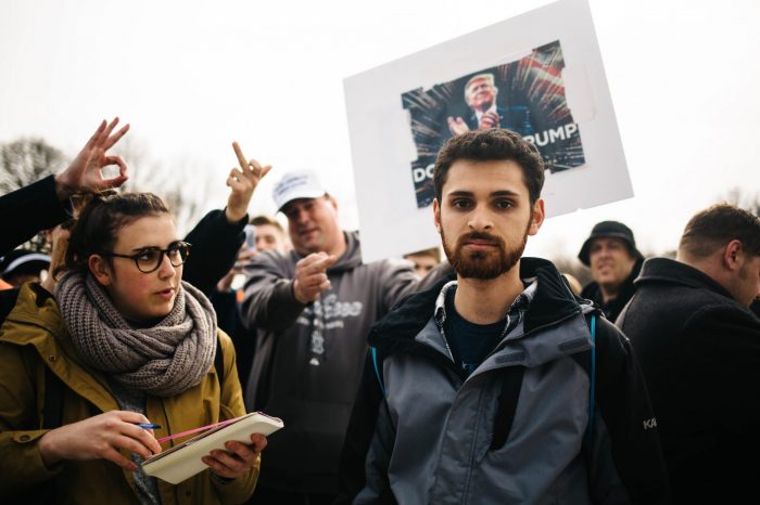 A group of protestors holding a photo of Donald Trump