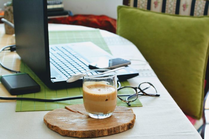 A cup of coffee next to a laptop 