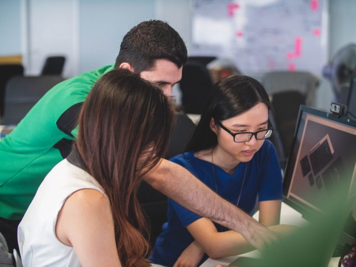 A man helping two women on a computer