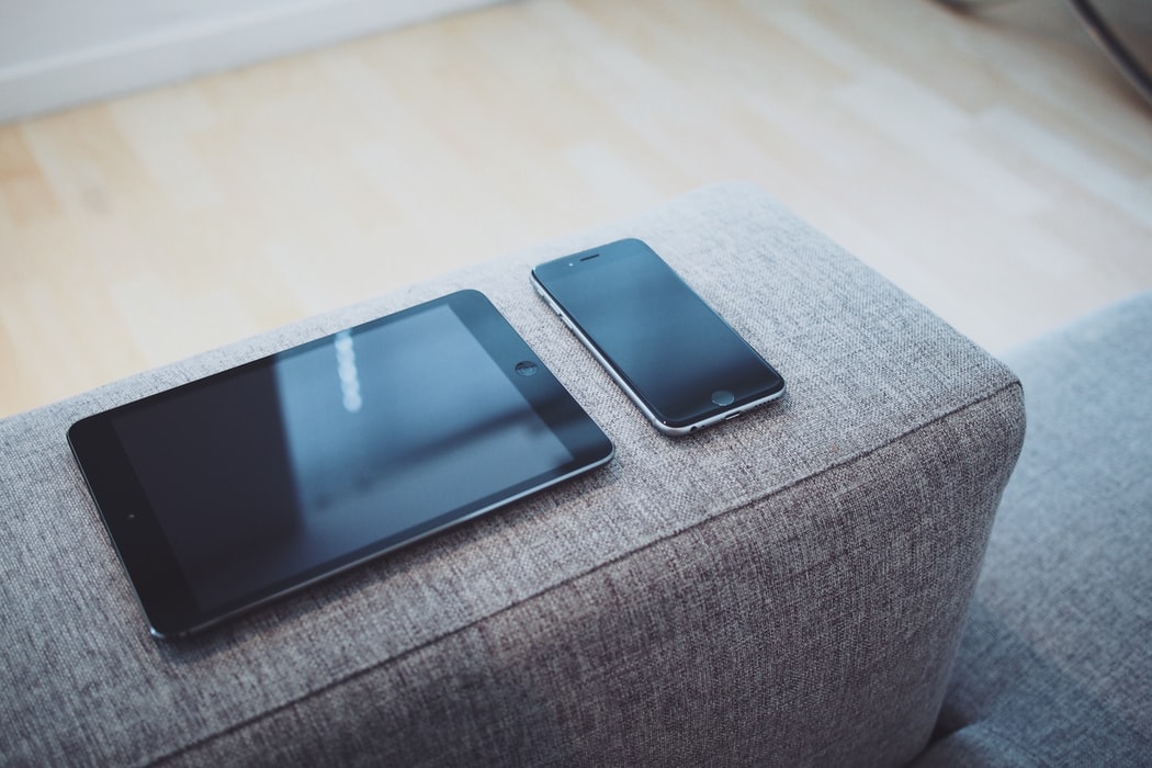 An iPad and iPhone on a couch