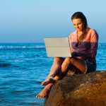 Woman working remotely on a beach