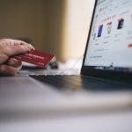 Consumer shopping online using computer with credit card in hand