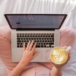 Woman sitting on bed with laptop