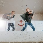 Two boys having a pillow fight on a bed