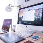 A computer, iPad, and iPhone on a desk